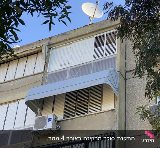 סוכך מרקיזה אפור מותקן מעל חלון בבית מגורים